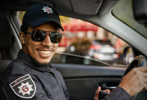 security guard in a car wearing sunglasses smiling