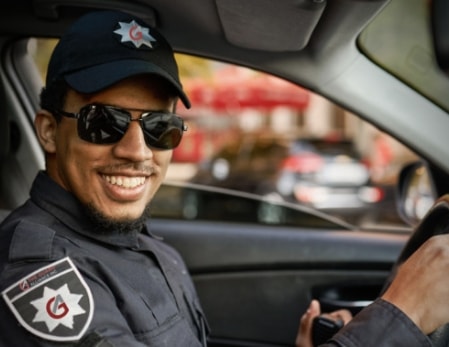 security guard in a car wearing sunglasses smiling