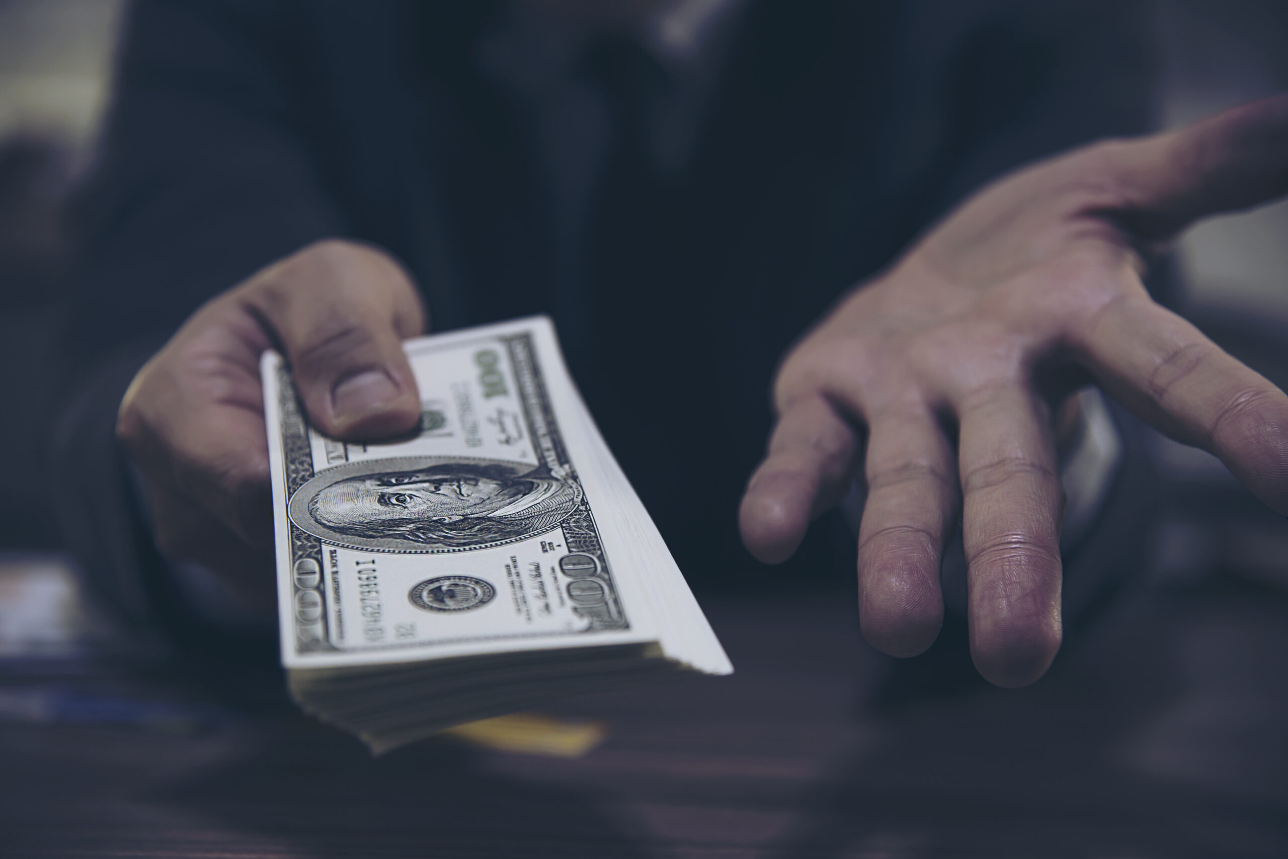 Bank teller man’s hands giving dollar banknotes