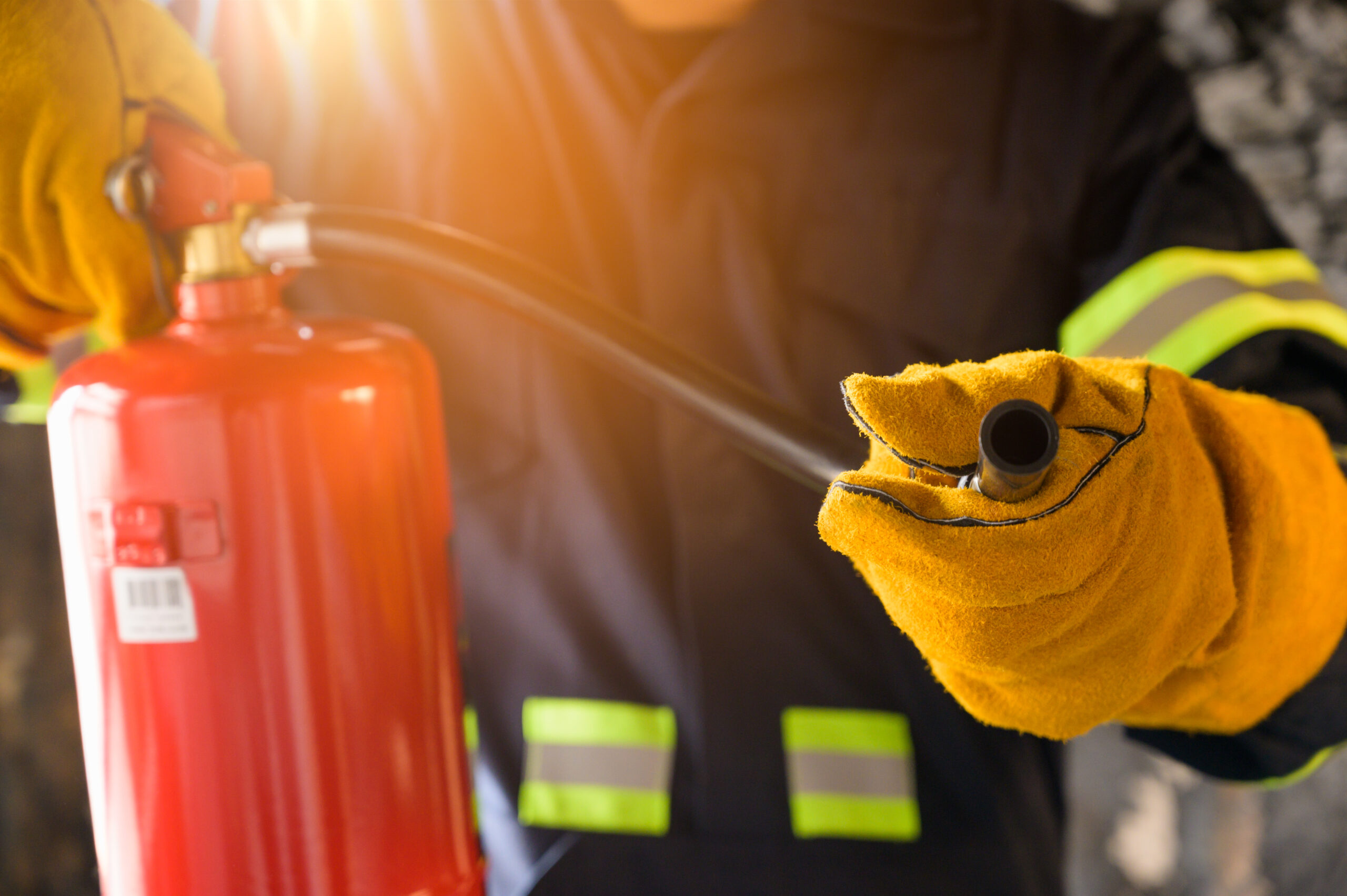 Close up hand Fireman using fire extinguisher fighting.