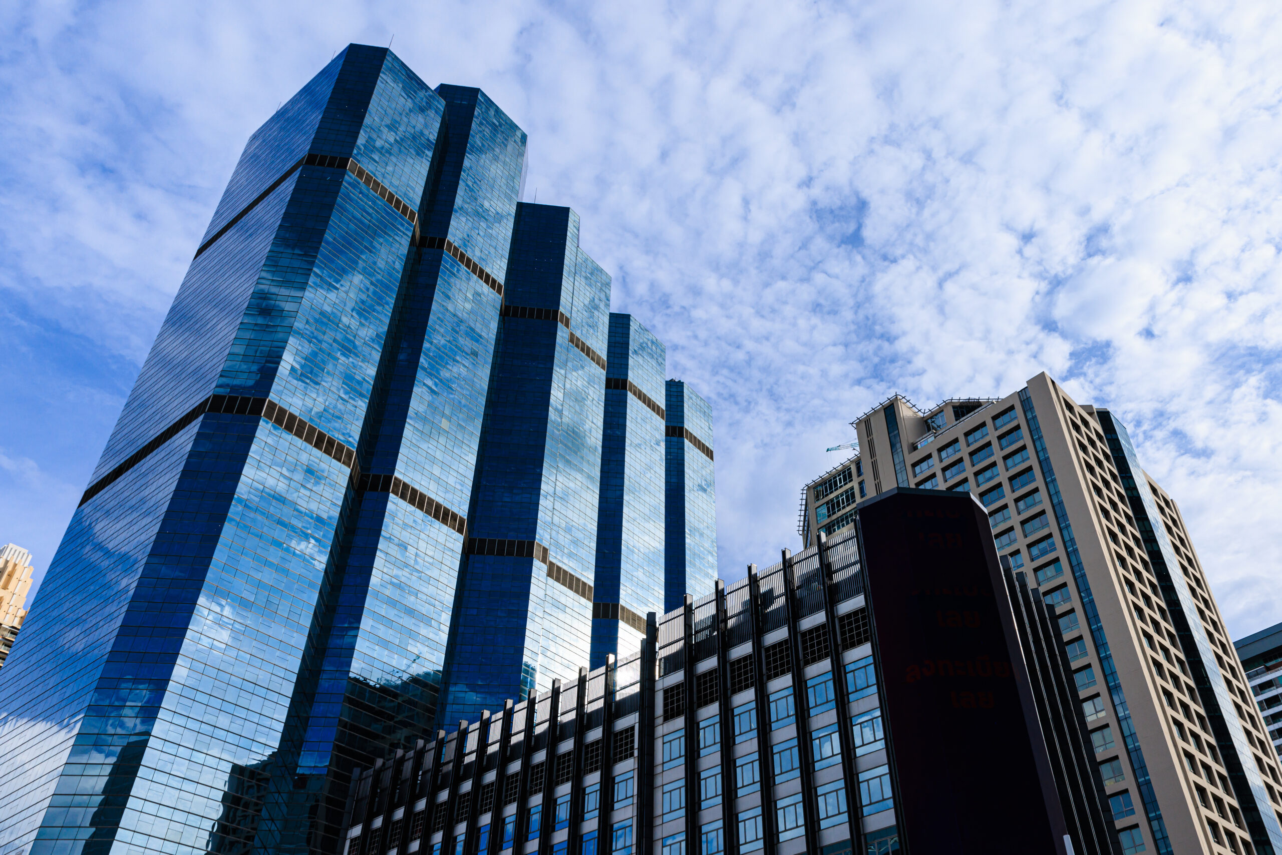 Blue sky and clouds reflected on the glass of office business bu