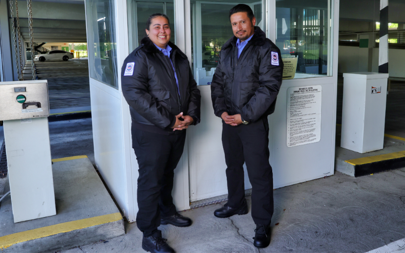 Two security guards face camera while protecting a parking structure